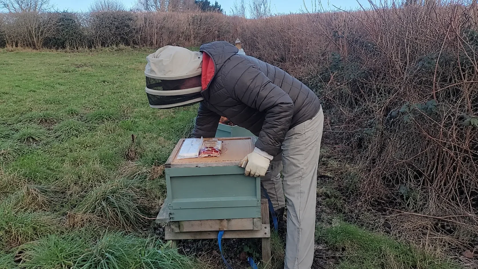 Me in my beekeeping veil and jacket making an external winter check on a wooden National hive